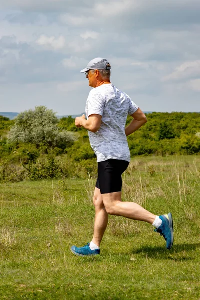 50-es caucasian man running on meadow — Stock Photo, Image