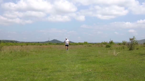 春の草原を走る中年のスポーティな男 — ストック動画