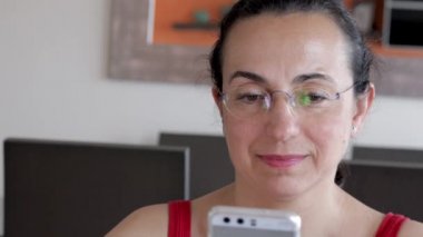 Evde cep telefonuna bakan güzel İspanyol kadın.