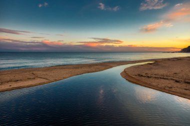 Costa Brava 'daki İspanyol plajından güzel bir gün batımı resmi.