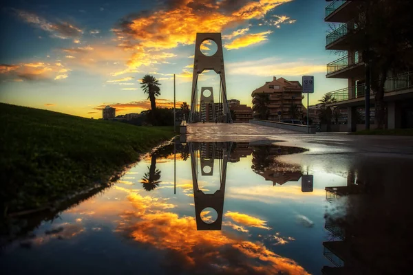 Reflexão colorida em poça depois da chuva para a frente uma ponte — Fotografia de Stock