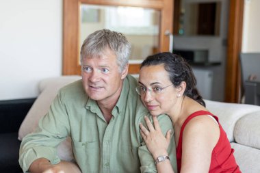 Orta yaşlı çift evdeki kanepede dinleniyor.