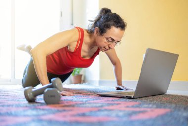 Güzel İspanyol kadın dizüstü bilgisayarda ders izliyor, oturma odasında eğitim görüyor.