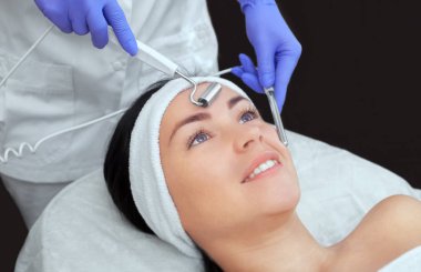 Kozmetik uzmanı bu aleti güzellik salonundaki genç ve güzel bir kadının mikro-akım terapisi için bir prosedür haline getiriyor. Kozmetoloji ve profesyonel cilt bakımı.