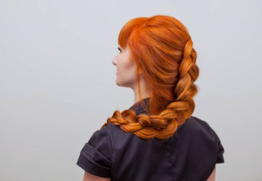 Uzun kızıl saçlı, örgülü güzel bir kız, bir güzellik salonunda. Profesyonel saç bakımı ve saç modelleri.