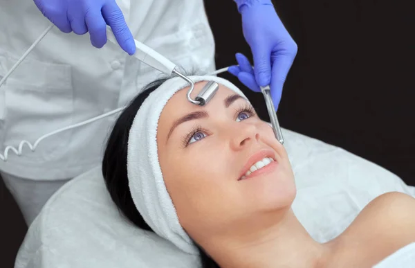 Kozmetik uzmanı bu aleti güzellik salonundaki genç ve güzel bir kadının mikro-akım terapisi için bir prosedür haline getiriyor. Kozmetoloji ve profesyonel cilt bakımı.