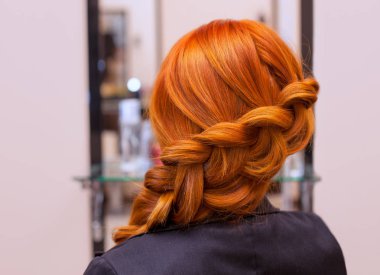Uzun kızıl saçlı, örgülü güzel bir kız, bir güzellik salonunda. Profesyonel saç bakımı ve saç modelleri.
