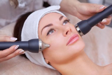 Kozmetik uzmanı bu işlemi güzellik salonundaki güzel, genç bir kadının yüz derisini ultrasonik olarak temizliyor. Kozmetoloji ve profesyonel cilt bakımı..