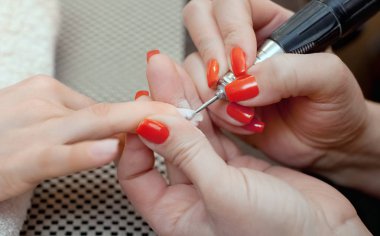 Manikür testeresinin ustası güzellik salonunda jöleli tırnak uzatma işlemi sırasında tırnak şekli takıyor. Eller için profesyonel bakım.