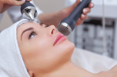 Kozmetik uzmanı bu işlemi güzellik salonundaki güzel, genç bir kadının yüz derisini ultrasonik olarak temizliyor. Kozmetoloji ve profesyonel cilt bakımı..