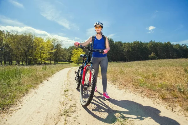Yksi Nuori Nainen Ajaa Maastopyörällä Kaupungin Ulkopuolella Tiellä Metsässä Kesäpäivänä — kuvapankkivalokuva