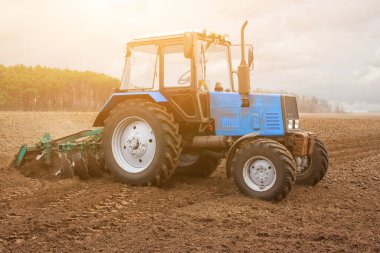 İlkbahar sabahı traktör gider ve ekinlerin inmesinden önce bir tarla sürme makinesini çeker. Dünyada geçen yılın ayçiçeğinin kuru sapları yatıyor..