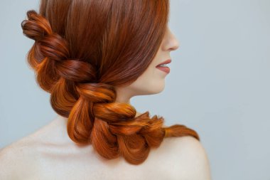 Uzun kızıl saçlı, örgülü güzel bir kız, bir güzellik salonunda. Profesyonel saç bakımı ve saç modelleri.