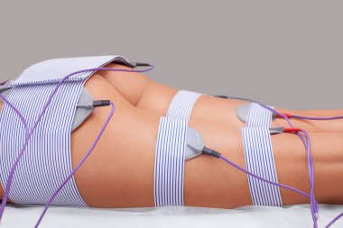 Güzellik salonundaki bir kadının bacaklarında ve kalçalarında miostimülasyon prosedürü. Vücuda özen göstermek, aşırı ağırlığı azaltmak..