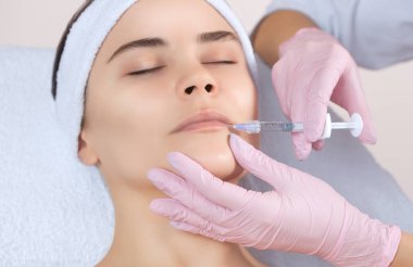 Doktor kozmetik uzmanı güzellik salonunda güzel bir kadının dudak büyütme prosedürünü yapıyor. Kozmetik cilt bakımı..