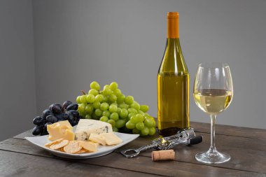 Bardak beyaz şarap şişe şarap, peynir ve üzüm ile