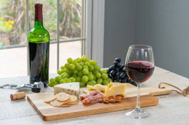 Kırmızı şarap şişe şarap, peynir, kraker, jambon, badem ve üzüm ile