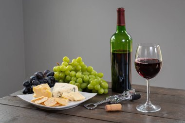 Bardak beyaz şarap şişe şarap, peynir ve üzüm ile