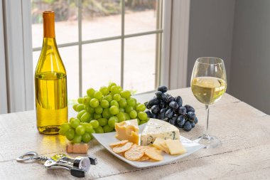 Bardak beyaz şarap şişe şarap, peynir ve üzüm ile