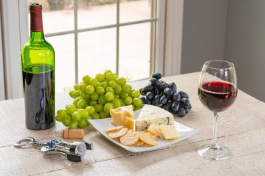 Bardak beyaz şarap şişe şarap, peynir ve üzüm ile