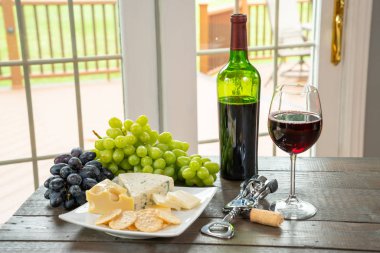 Bardak beyaz şarap şişe şarap, peynir ve üzüm ile