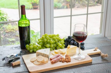 Kırmızı şarap şişe şarap, peynir, kraker, badem ve üzüm ile