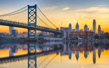 Philadelphia sunset skyline and Ben Franklin Bridge refection from across the Delaware River clipart