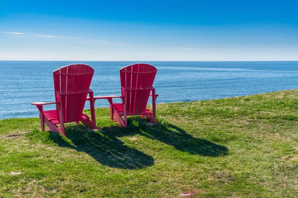 Zwei rote adirondack-Stühle entlang der Küste von Neufundland — Stockfoto