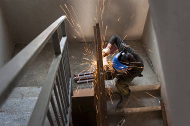 İnşaat alanında çalışıyor. Açı öğütücüsünde çalışıyor.