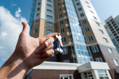 mavi gökyüzüne karşı yeni bir çok katlı apartman elinde anahtarları