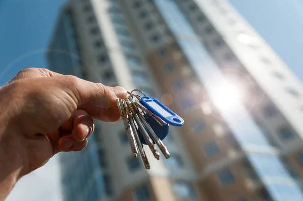 Keys in hand from a new multi-storey apartment building against the blue sky Stock Picture