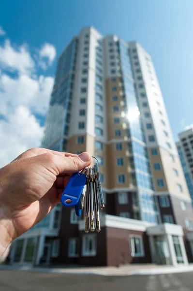 Keys in hand from a new multi-storey apartment building against the blue sky Stock Photo