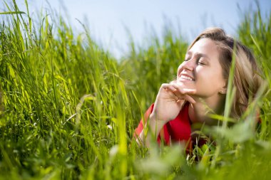 yaz aylarında bir alanda yeşil çim oturan kırmızı elbiseli bir kız
