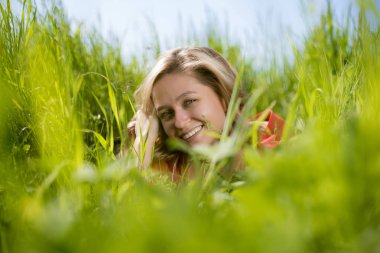 yaz aylarında bir alanda yeşil çim oturan kırmızı elbiseli bir kız