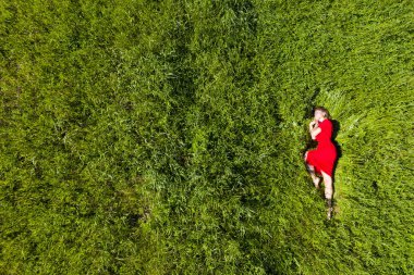 yeşil çim bir alanda kırmızı bir elbise içinde yatan kız drone kaldırıldı