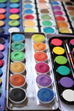Stüdyoda farklı suluboya boya kutuları var.