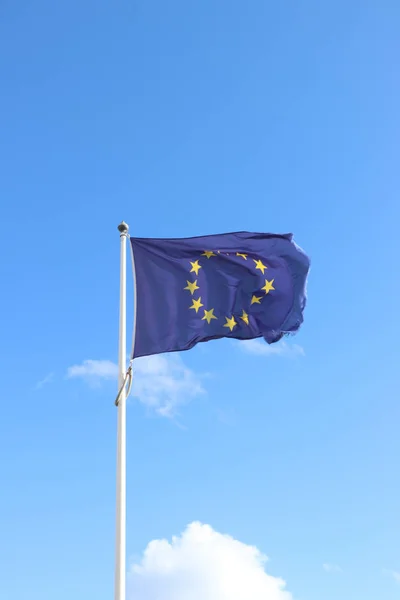 The blue European Union Flag against blue sky, frayed