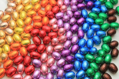 Bir grup folyo sarılıp gökkuşağı renklerine bürünmüş çikolatalı yumurta.