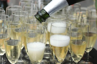 Pouring champagne in stylish glasses, served on a wedding reception clipart