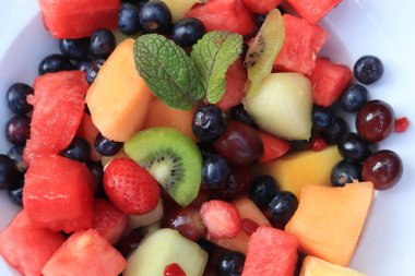 Parlak renklerde taze meyve salatası, taze nane yapraklarıyla süslenmiş.