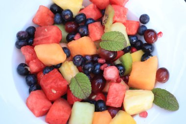 Parlak renklerde taze meyve salatası, taze nane yapraklarıyla süslenmiş.
