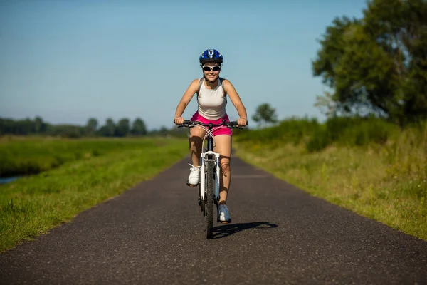 若い女性は自転車を田舎に乗ってます スポーツとレジャーの概念 — ストック写真