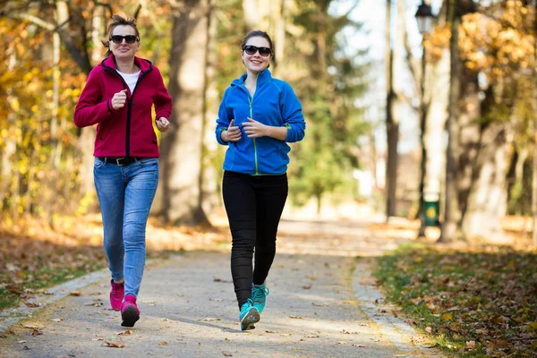 Δύο Γυναίκες Που Τρέξιμο Μαζί Στο Φθινοπωρινό Πάρκο — Φωτογραφία Αρχείου