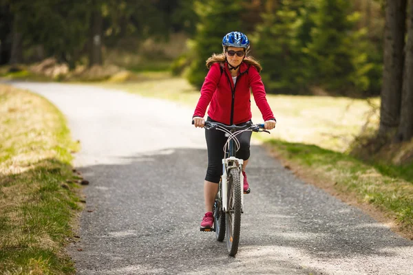 活跃的成年妇女在运动服骑自行车在领域 体育和活动概念 — 图库照片