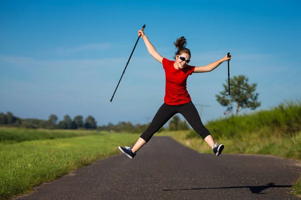 Mujer Joven Ropa Deportiva Saltando Divirtiéndose Con Palos Turísticos —  Fotos de Stock