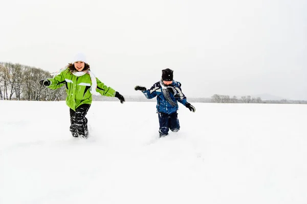 Kids playing with snow and having fun in winter park