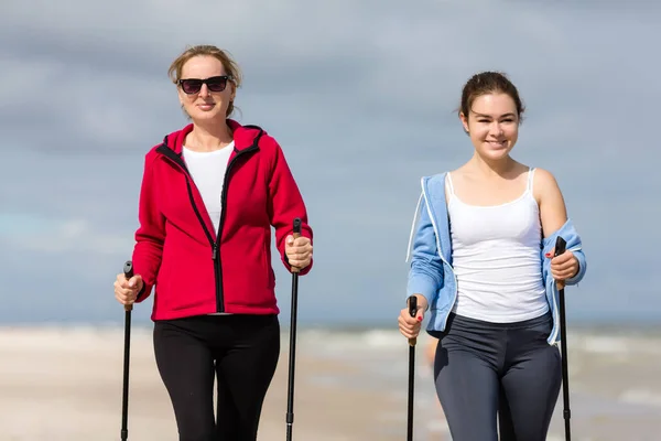 きれいな海辺で観光スティックと一緒に歩く女性 ノルディック ウォーキング — ストック写真