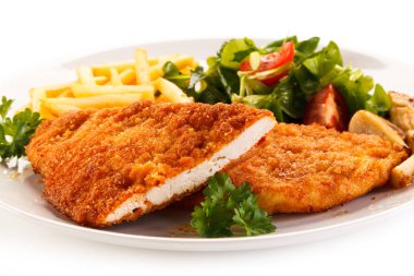 Detail view of chicken schnitzel with french fries and vegetable salad on white plate clipart
