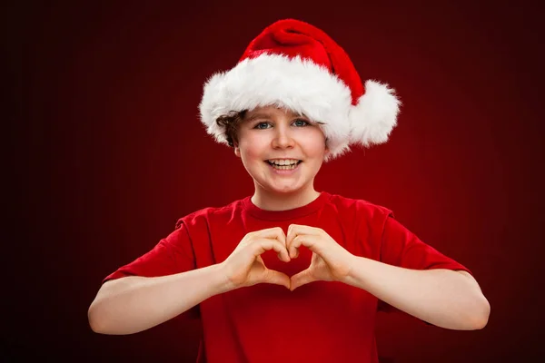 Menino Chapéu Santa Mostrando Símbolo Coração Gradiente Vermelho Fundo Preto — Fotografia de Stock