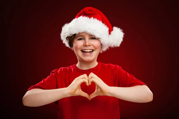 Αγόρι Στο Santa Καπέλο Δείχνει Καρδιά Σύμβολο Κλίση Φόντο Κόκκινο — Φωτογραφία Αρχείου